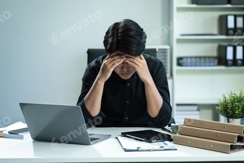Preview: Young stressed Asian businessman working in the office.
