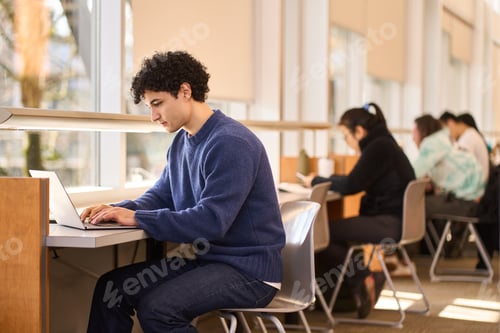 Preview: Multitasking, overworked, serious Latin American student, online studying in a modern library campus