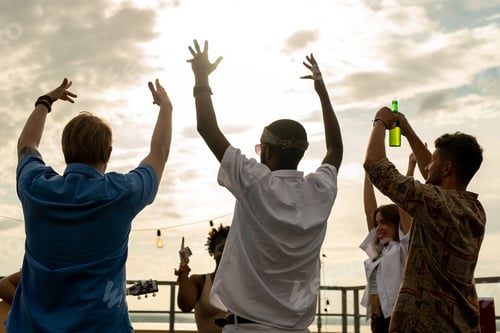 Preview: Joyful friends with beer raising arms while dancing