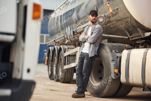 Preview: Leaning on the vehicle. Young truck driver in casual clothes