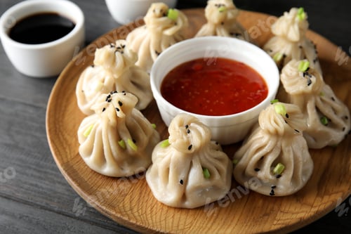 Preview: Wooden plate with tasty baozi dumplings and sauce on table, closeup