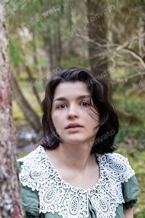 Preview: a young woman in a green cotton dress with a vintage collar in the forest among the branches