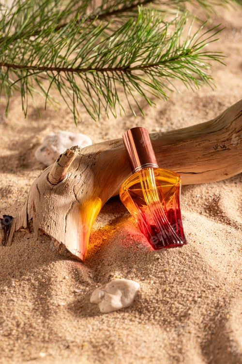 Preview: Sophisticated red perfume on sandy beach in summer.