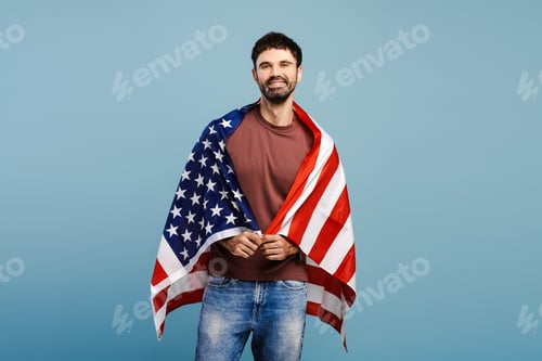 Preview: Handsome, smiling man holding American flag looking at camera. USA independence day concept