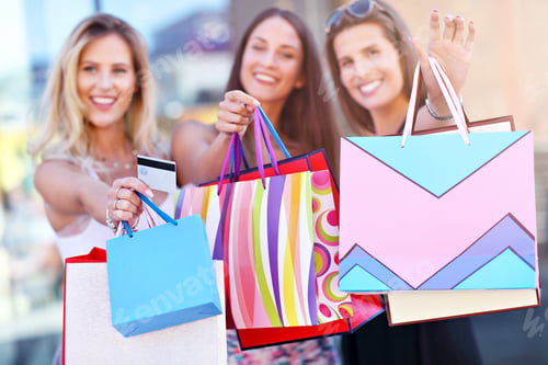 Preview: Happy girl friends shopping in mall