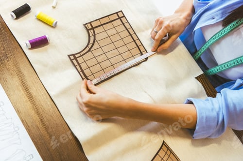 Preview: cropped image of seamstress measuring pattern at table