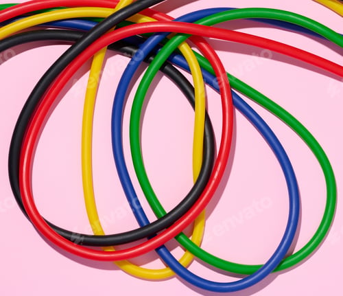 Preview: Multicolored rubber tubes on a pink background, top view
