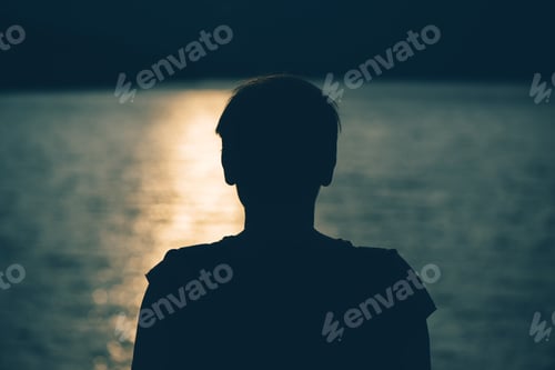 Preview: Silhouette of depressed sad woman standing by the lake