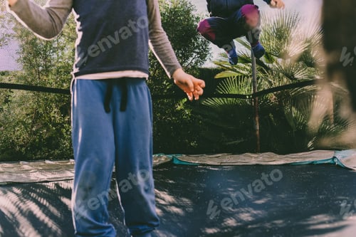 Preview: Children jumping on a trampoline enjoying a sunny spring day.