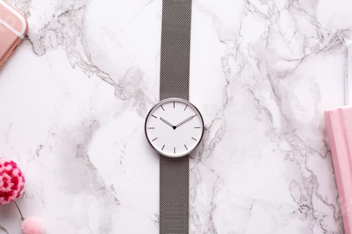Preview: Clock and pink notebook on a marble background in the office