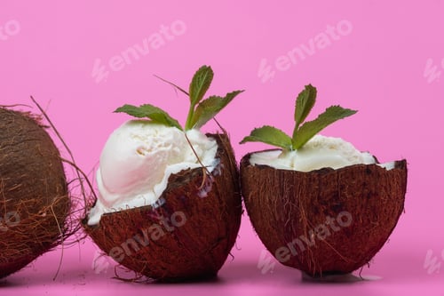 Preview: Vanilla ice cream balls in fresh coconut halves decorated with mint leaves on a pink background