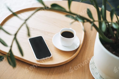 Preview: Top view of smartphone screen and cup of coffee through green houseplant