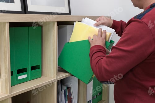 Preview: man takes folders with documents from the shelves