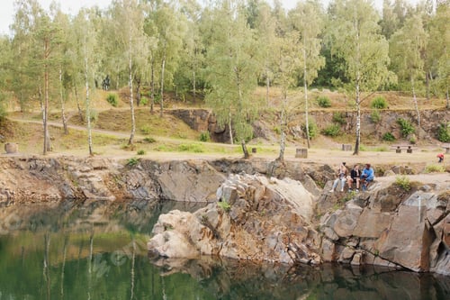 Preview: Mid distance of friends sitting on rock by lake