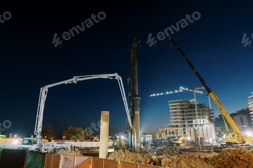 Preview: Illuminated drilling rigs work at night on a construction site