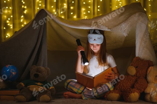 Preview: Little girl are reading a book with flashlights in tent.