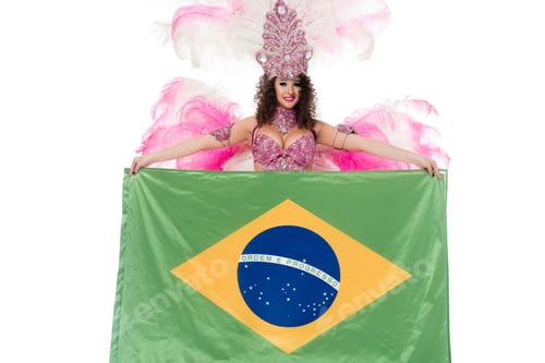 Preview: Bright woman in carnival costume with pink feathers holds large flag of Brasil isolated on white