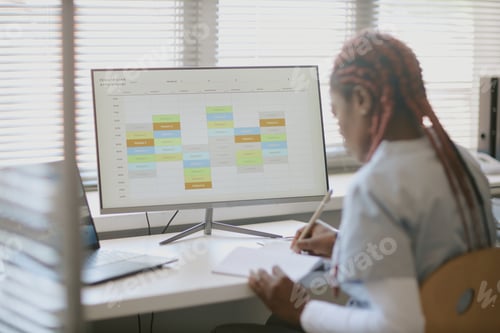 Preview: Studying a Calendar on Computer Screen in Modern Office