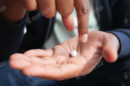 Preview: Close-Up of Hand Holding Small Vitamin or Medicine Tablet