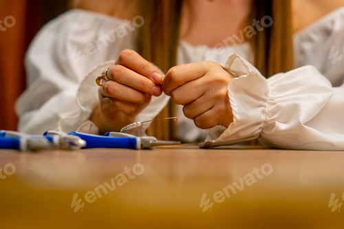 Preview: close-up hands of a young girl makes jewelry with her own hands cuts the remnants of wire necklace
