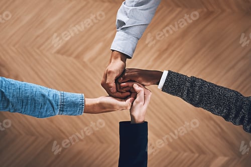 Preview: High angle shot of a group of unidentifiable businesspeople joining their hands together in unity