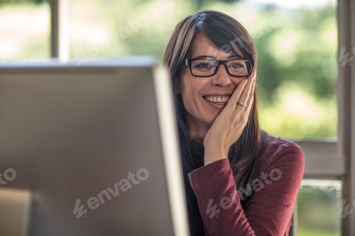 Preview: Happy businesswoman with hand on face at home desk