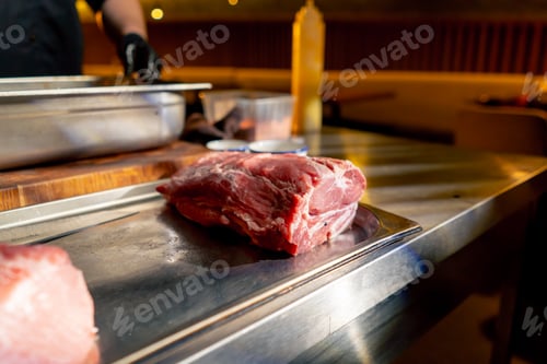 Preview: close-up in a restaurant on an iron table there are professional dishes with fresh piece of meat