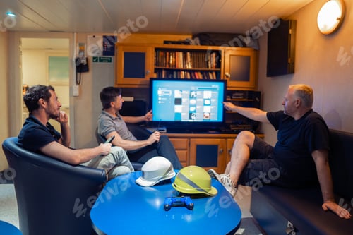 Preview: Happy team of ship officers watch TV onboard of vessel