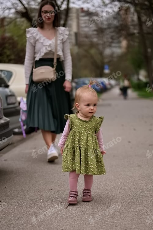 Preview: Little baby girl and her mother walking down the street