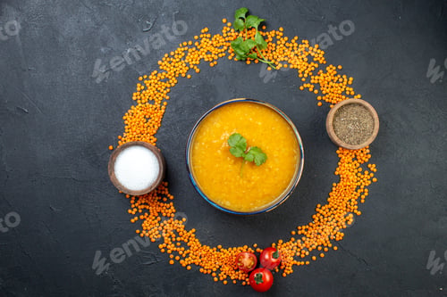Preview: Top view of red lentils lined up in a circle and delicious soup salt pepper on black background with