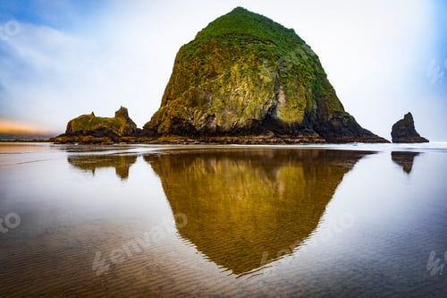 Preview: Beautiful view of Haystack Rock reflected on water in Canon Beach, Oregon