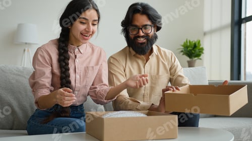 Preview: Happy couple customers receive parcel look inside box Arabian Indian man and woman open delivery