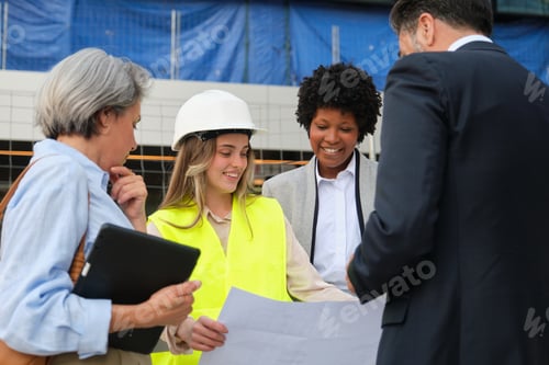Preview: Team of architects and engineers reviewing blueprints on construction site