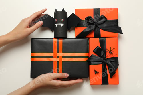 Preview: Gift boxes, paper bat and hands on white background, top view