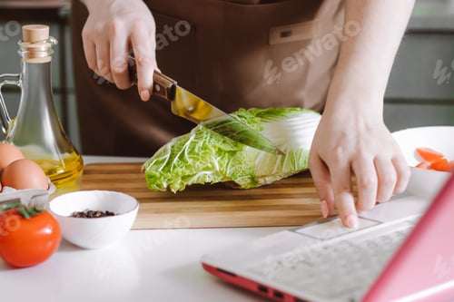 Preview: Online cooking. Preparing salad using digital cookbook. Fresh vegetables and laptop in home kitchen.