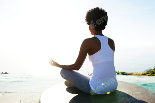 Preview: Young woman sitting at beach in yoga pose