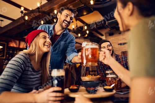 Preview: Young carefree people toasting while gathering for a beer in bar.