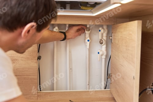 Preview: Man opens an assembly hatch and checks water pipes