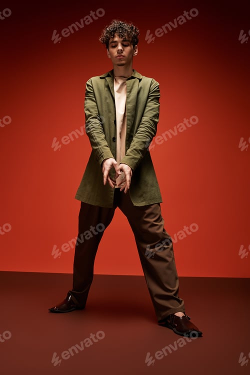 Preview: Stylish young man in a bold pose against a striking red backdrop showcasing modern fashion