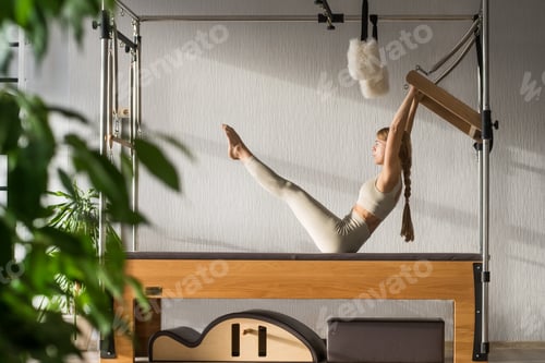 Preview: Pilates fitness trainer doing exercises on in pilates studio. Balanced Body Cadillac machine for