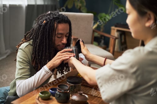 Preview: Young Adult Black Man Smelling Tea Leaves with Young Adult Asian Woman Assisting