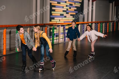 Preview: Happy kids holding hands while training on roller rink
