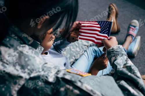 Preview: back view of african american daughter and female soldier in military uniform with american flag at
