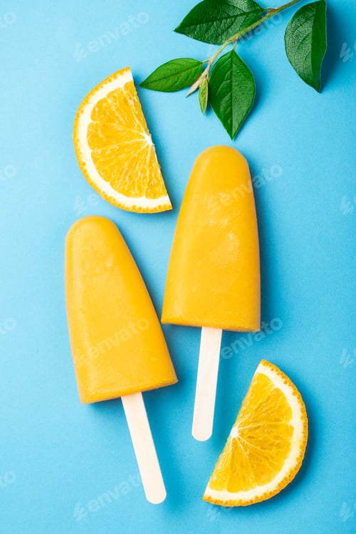 Preview: Orange popsicles with juice on a blue background. Ice pops, flat lay, top view
