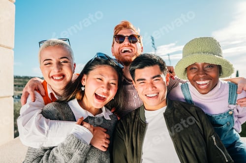 Visualização: Cinco amigos multiétnicos posando para uma foto sorrindo e se divertindo ao ar livre.