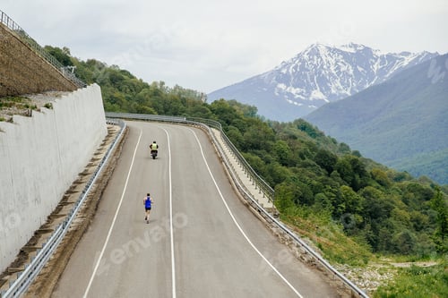 Vista previa: atleta líder corriendo cuesta arriba en una carrera de maratón en carretera para escolta de motociclistas
