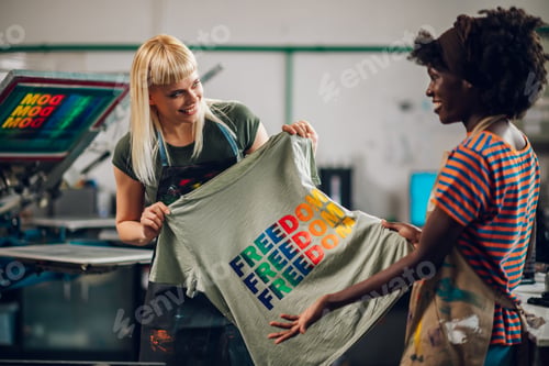 Preview: Multiracial printing shop workers doing quality control of printed shirt