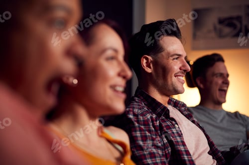 Preview: Group Of Friends Sitting On Sofa At Home Watching Evening TV And Relaxing Together