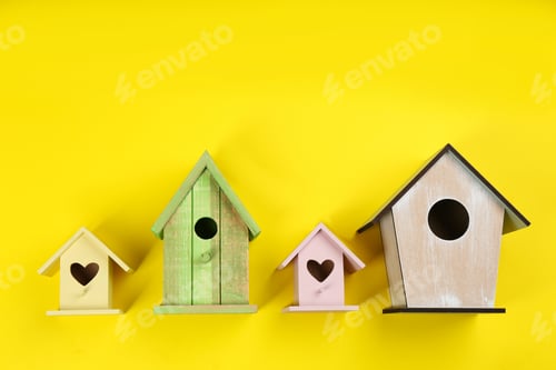 Preview: Collection of handmade bird houses on yellow background, flat lay