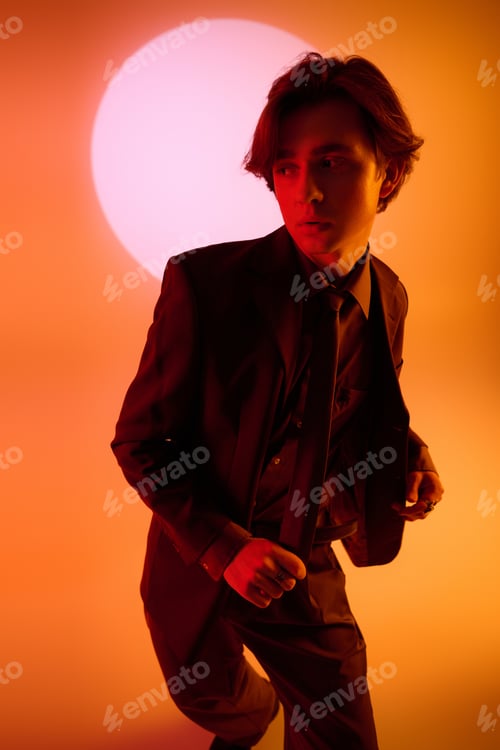 Preview: Stylish young man strikes a pose against a dramatic sunset backdrop with vibrant hues